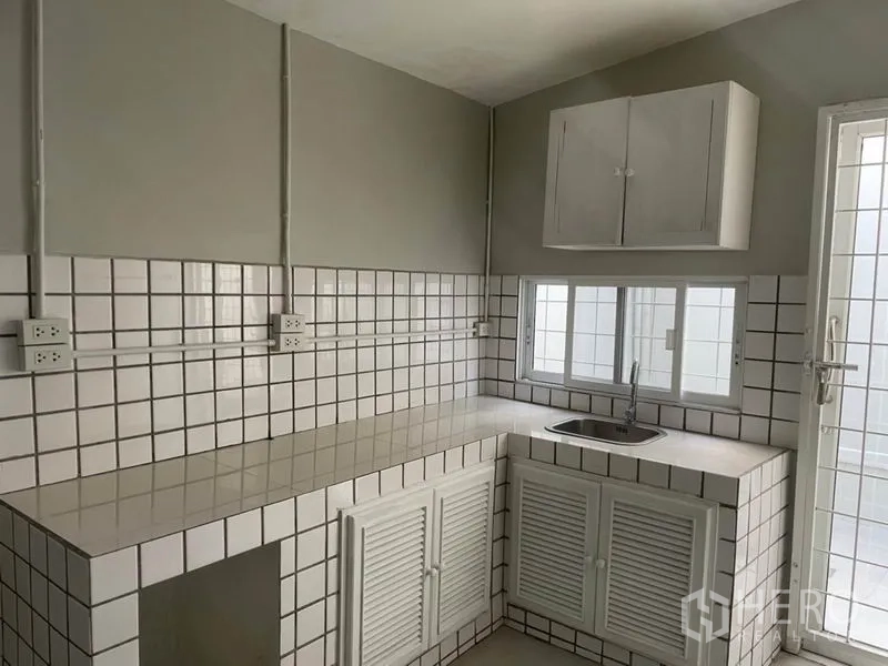 Detached House for rent in Huai Khwang, Bangkok - Compact Thai kitchen with tiled countertops, white cabinetry and a stainless sink.