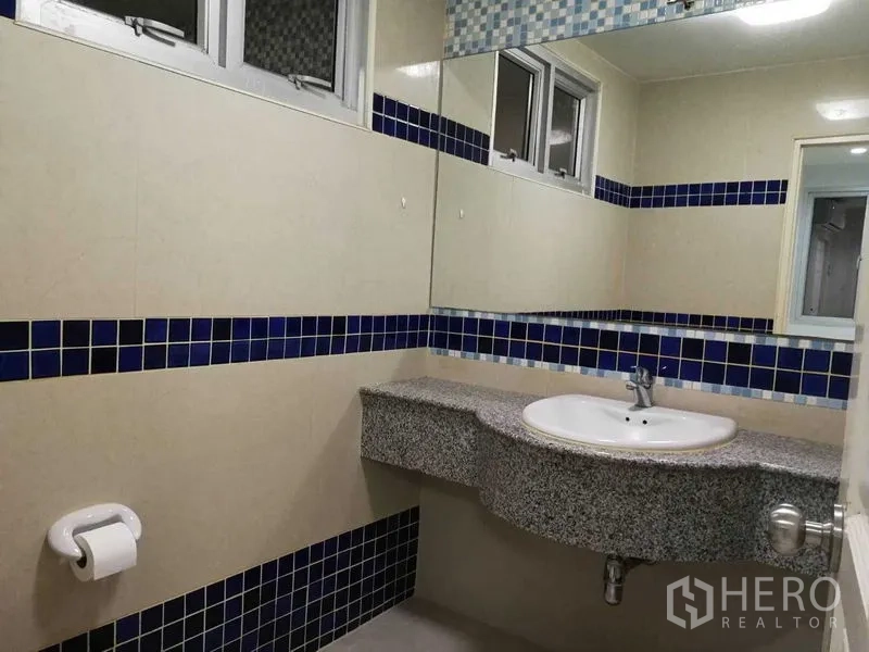 Home Office for rent in Khlong Toei, Bangkok - Bathroom with long mirror, granite countertop and blue mosaic tile accents.