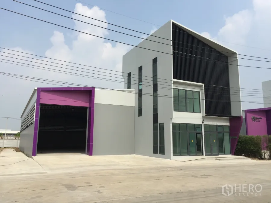 Factory for sale in Lam Luk Ka, Pathum Thani - Modern factory exterior with two-storey glass office and wide truck access bay.
