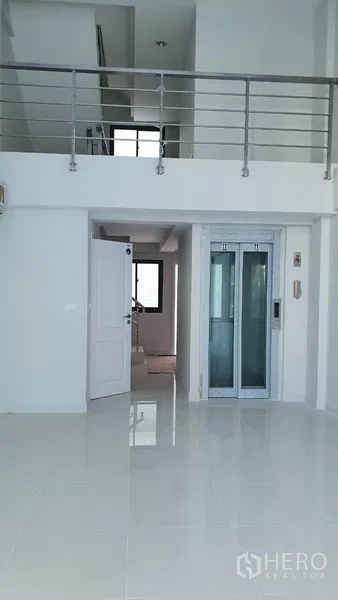 Home Office for rent in Suan Luang, Bangkok - Double‑height foyer with mezzanine railing and a private lift at the center.
