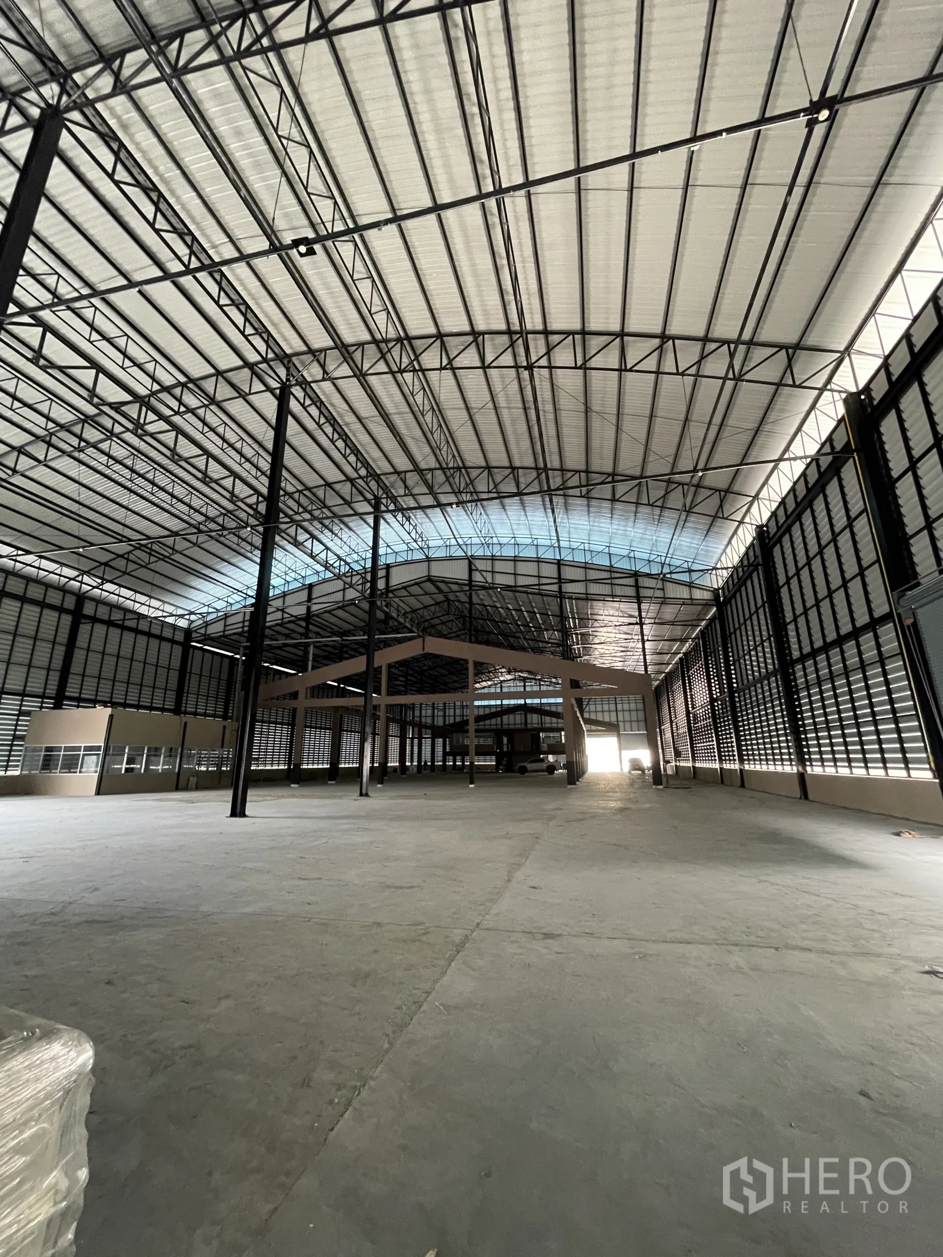 Factory for rent in Chon Buri - Spacious warehouse interior with high clear height, steel trusses, and skylight panels.