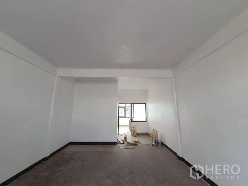 店屋 出租在Bangkok - 店屋室内，白色墙面与天花梁，尽端设大窗，采光明亮，地面有翻修材料