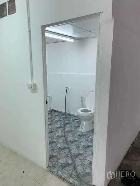 Warehouse for rent in Mueang Pathum Thani, Pathum Thani - Warehouse restroom with toilet, handheld bidet and patterned tile flooring.