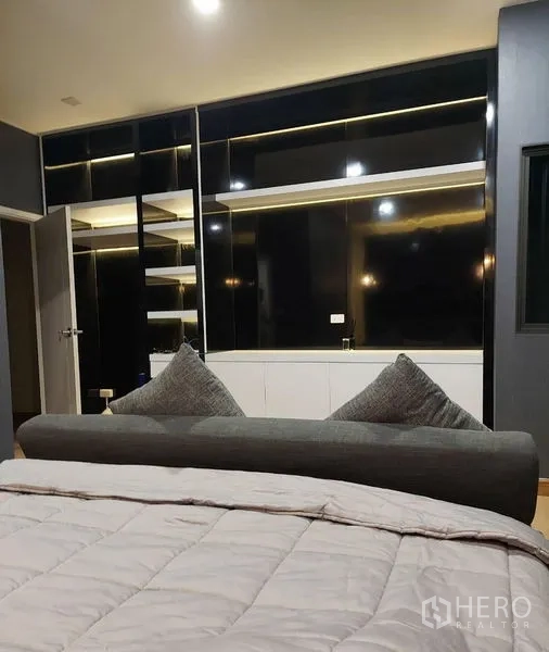 Townhouse for rent in Thanyaburi, Pathum Thani - Master bedroom with built-in black wardrobes, shelving, and ambient strip lighting.