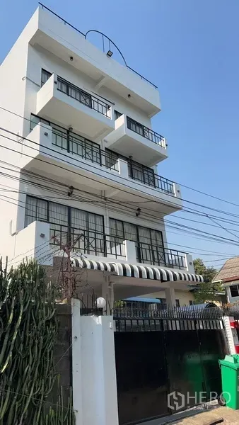 Home Office for rent or sale in Phra Khanong, Bangkok - Street view of gated modern home office with striped awning and multiple balconies.