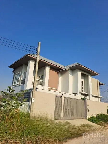 Detached House for rent in Prawet, Bangkok - Modern two-storey detached house in Prawet, Bangkok with a walled gate under a clear blue sky.