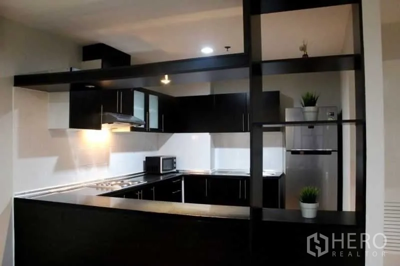 Condominium for rent in Khlong Toei, Bangkok - Modern U-shaped kitchen with black cabinetry, stainless counters and appliances.