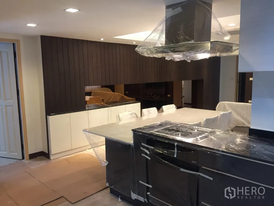 Condominium for rent in Pathum Wan, Bangkok - Modern Pathum Wan Bangkok condo kitchen with large island, range hood and wood panel feature wall.