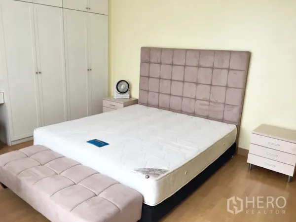 Condominium for rent in Khlong Toei, Bangkok - Bedroom with padded headboard, bench seat, side tables, and built-in wardrobes.