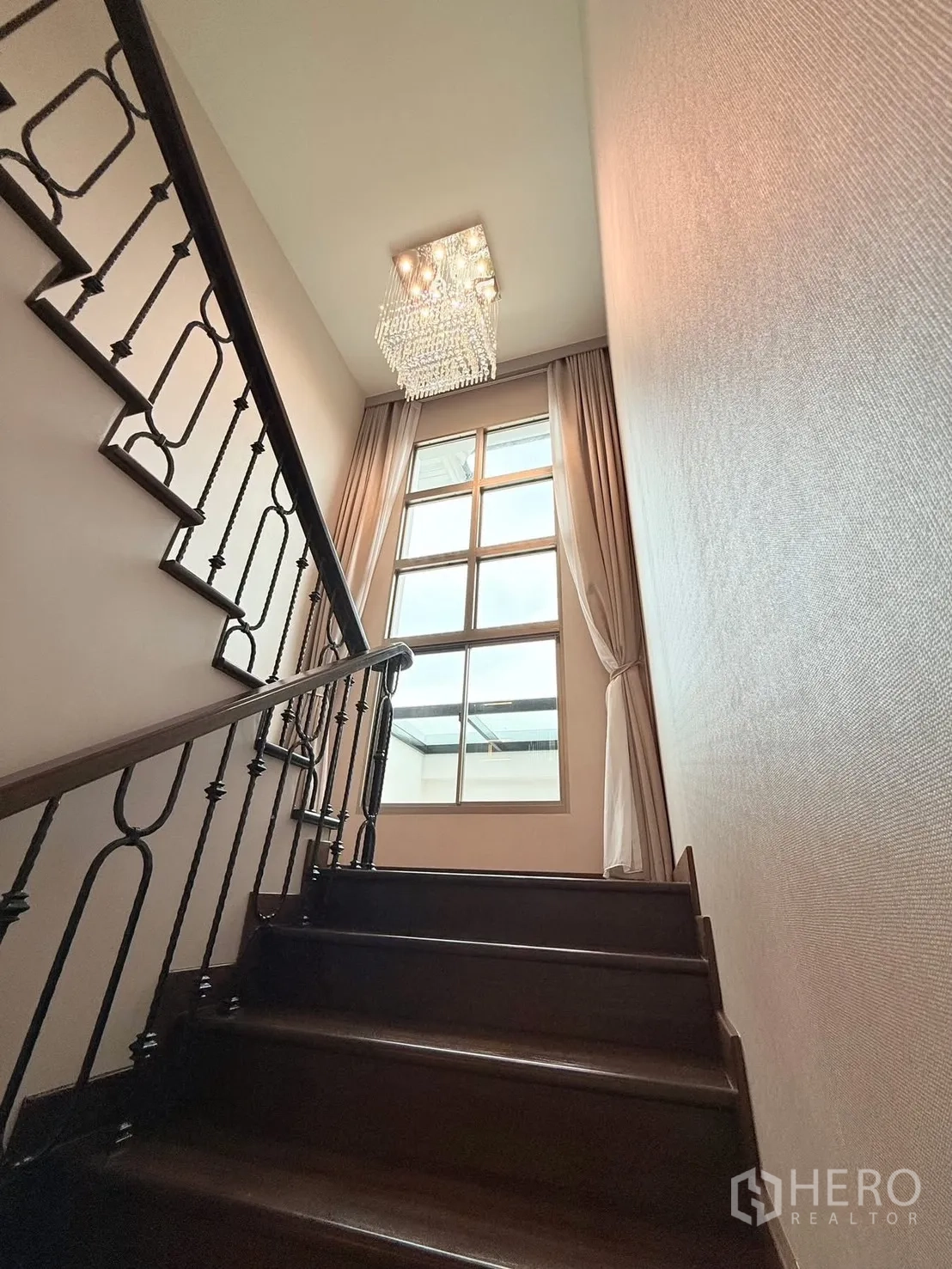 Detached House for rent or sale in Bang Phli, Samut Prakan - Staircase ascending with wrought-iron railing, chandelier and tall window.
