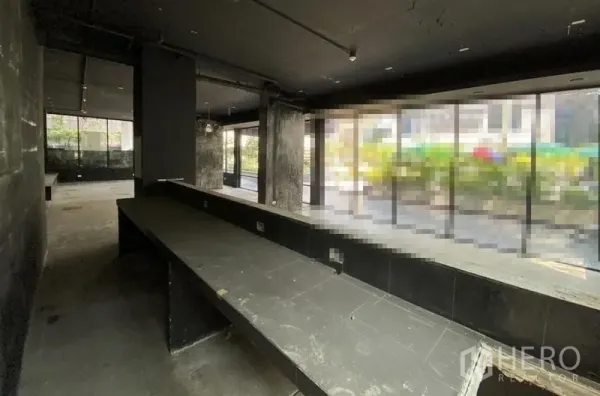 Retail Space for rent in Khlong Toei, Bangkok - Dark-shell retail unit with long service counter and floor-to-ceiling windows.