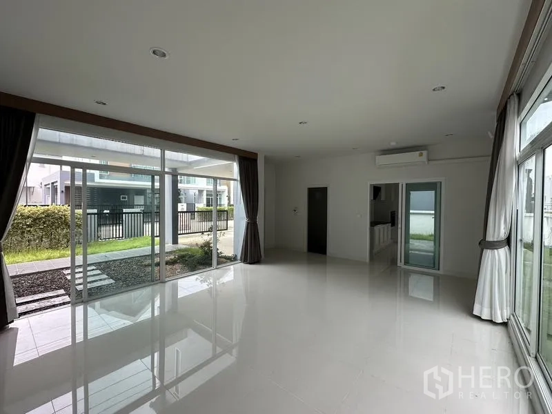 Detached House for sale in Lam Luk Ka, Pathum Thani - Front-facing living area with wide glass walls opening to the gate and yard.