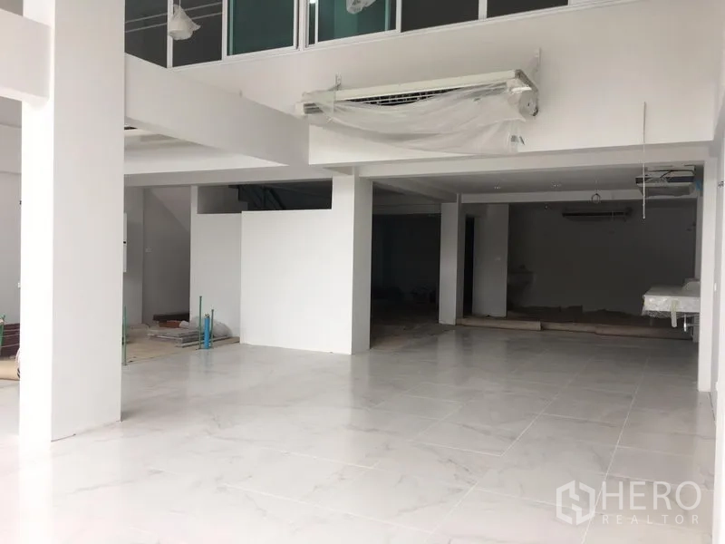 Shophouse for rent in Bang Na, Bangkok - Bright open-plan shophouse ground floor with white tile flooring, pillars and a mezzanine-ready layout near BTS Udom Suk.