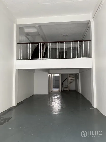 Retail Space for rent in Watthana, Bangkok - Deep, double-height shop space with mezzanine railing and white walls.
