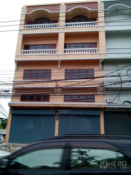 Shophouse for rent in Phra Khanong, Bangkok - Four-storey shophouse facade with balconies and metal shopfront shutters.