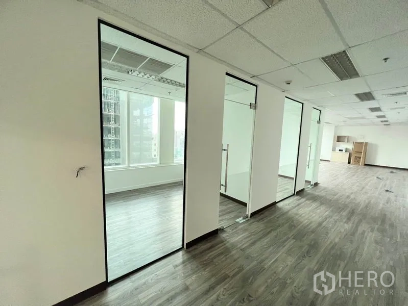 Office Space for rent in Watthana, Bangkok - Row of glass-partitioned rooms and meeting spaces along a corridor with natural light and city views.