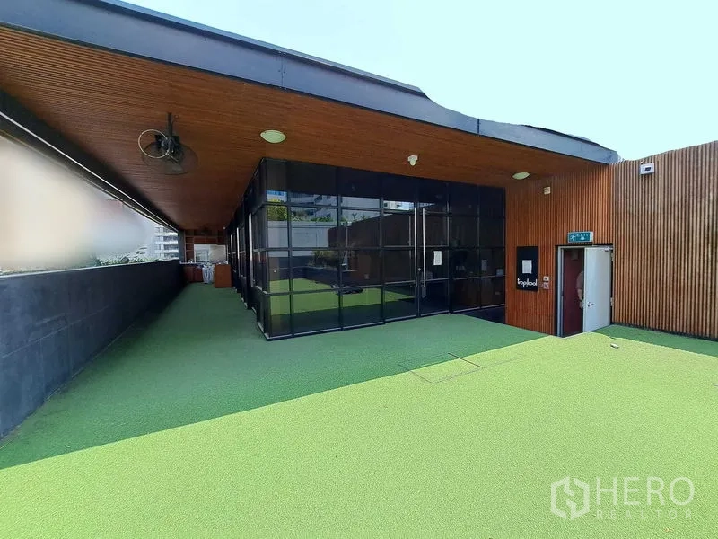 Retail Space for rent in Khlong Toei, Bangkok - Glass-fronted retail space opening to a covered terrace and large artificial grass rooftop.