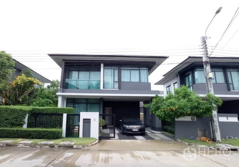 Detached House for rent in Bang Kapi, Bangkok - Modern two-storey detached house with gated entrance and covered carport on a quiet street.