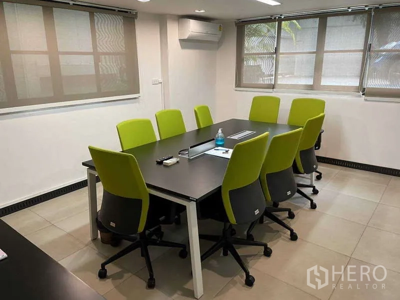 Home Office for rent in Watthana, Bangkok - Bright meeting room with black table and eight lime chairs beside windows.
