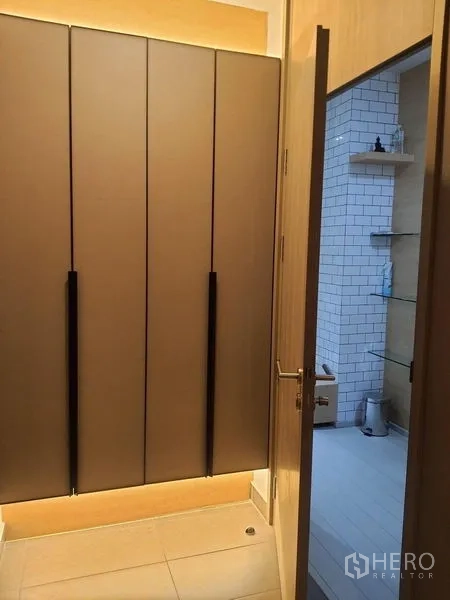 Condominium for rent in Pathum Wan, Bangkok - Hallway with built-in wardrobe leading to a bathroom finished with white subway tiles.