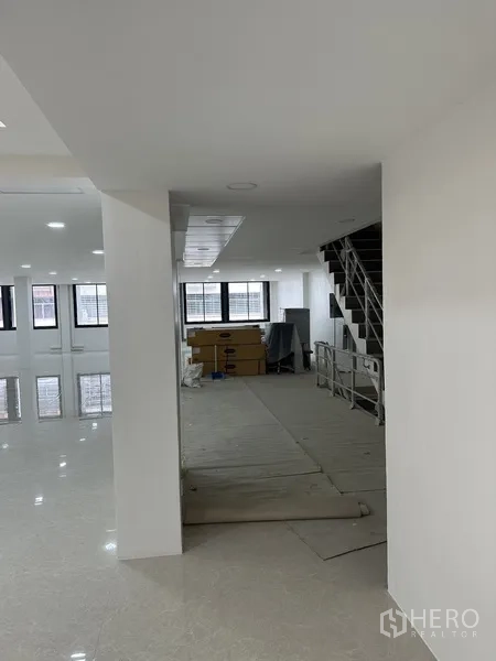 Office Space for rent or sale in Huai Khwang, Bangkok - Corridor linking stair to open-plan floor with boxes near the windows.