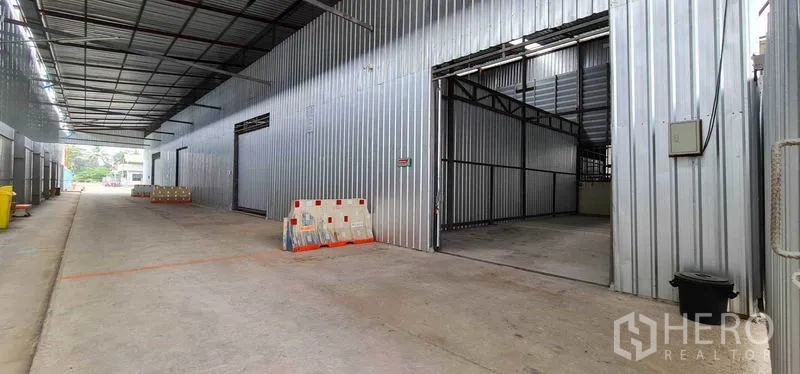 Warehouse for rent in Pak Kret, Nonthaburi - Covered drive‑through aisle with multiple unit entrances and generous turning space.