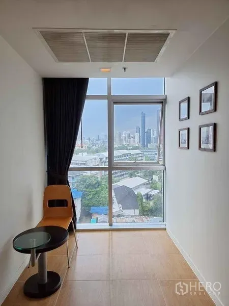 Condominium for rent in Khlong Luang, Pathum Thani - Window nook with chair and side table offering city view near BTS Ekkamai.