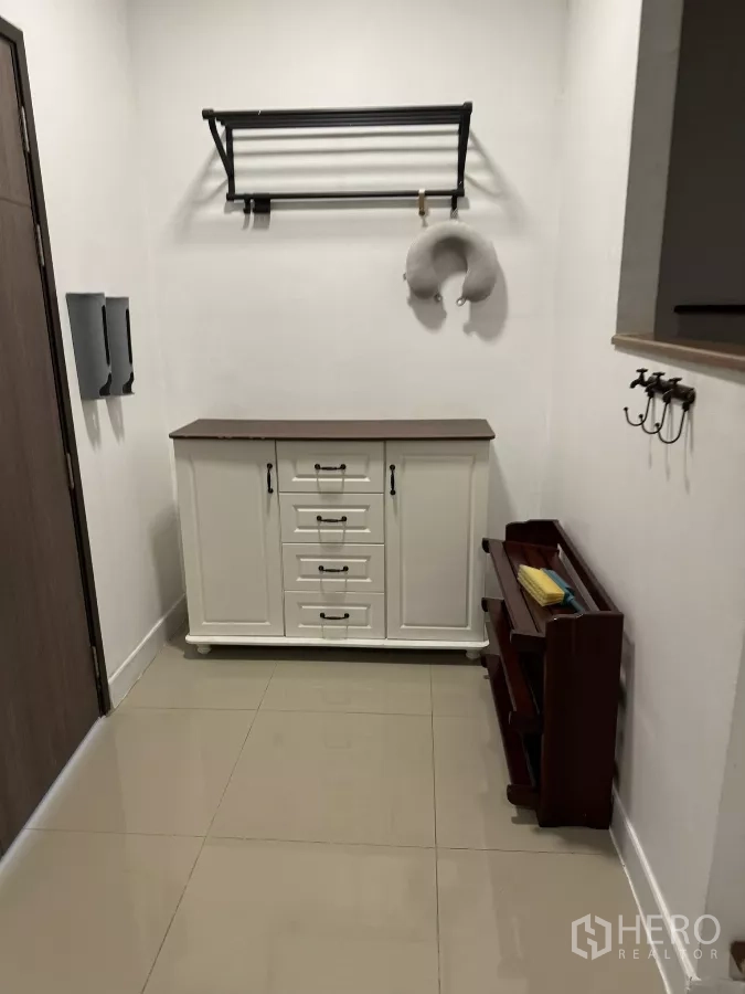 Townhouse for rent in Suan Luang, Bangkok - Entry hallway showing cabinet, hooks, and shoe rack on polished tile floor.