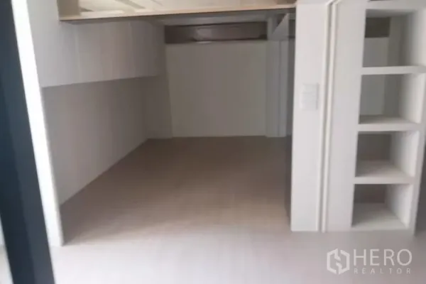 Retail Space for rent - Empty white room with built-in cabinets and open shelving, ready for tenant fit-out.