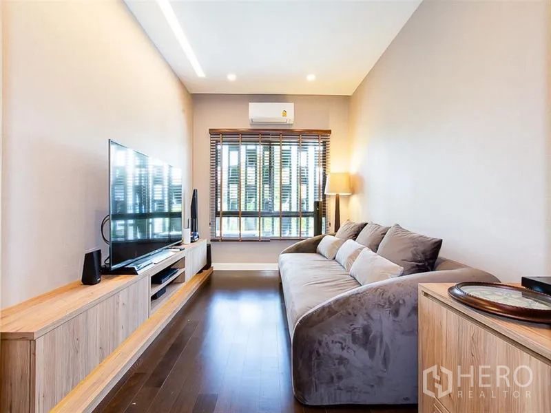 Detached House for rent or sale in Prawet, Bangkok - Cozy family media room with sofa, TV console and wooden flooring.
