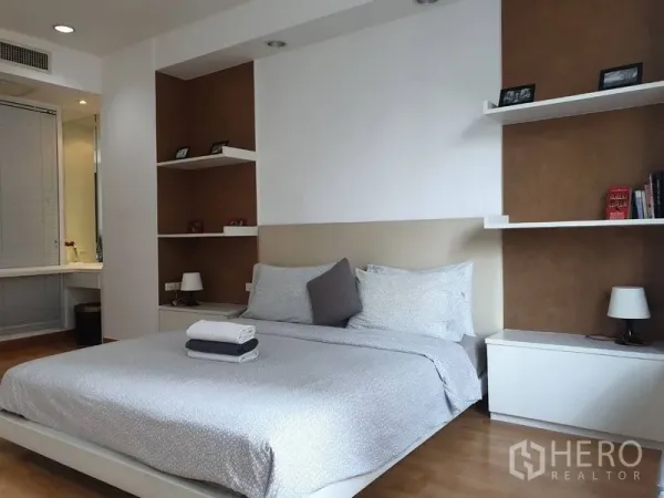 Condominium for rent in Khlong Toei, Bangkok - Spacious master bedroom with king bed, recessed shelving, and a glimpse of the ensuite vanity.