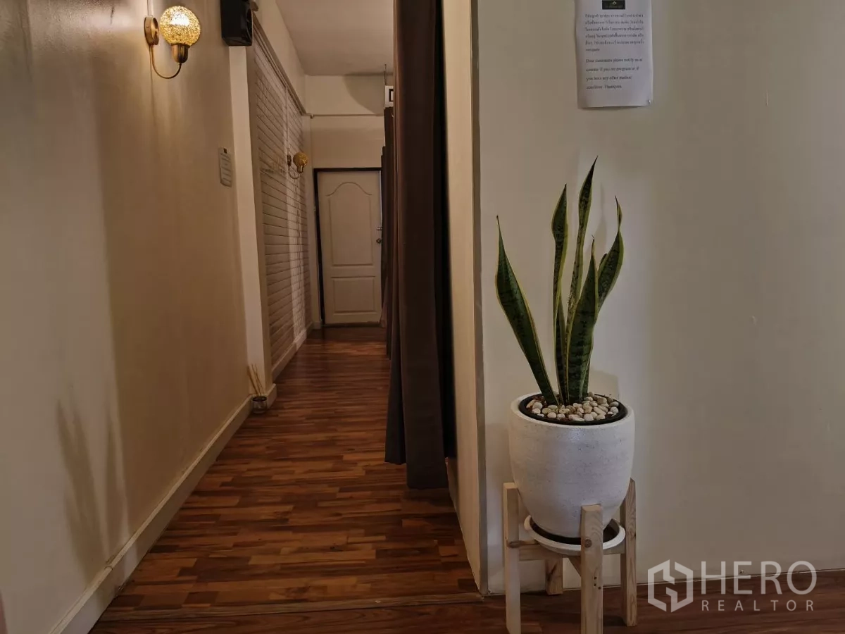 Shophouse for rent in Watthana, Bangkok - Hallway with wooden flooring, wall sconces and a potted plant.