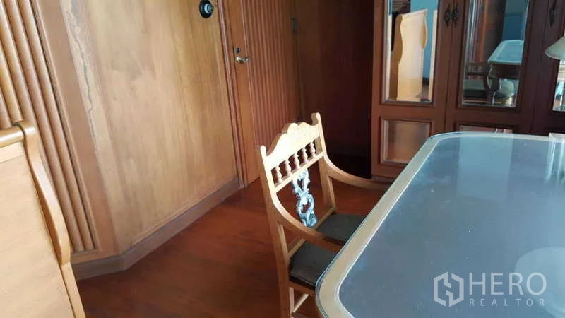 Townhouse for rent in Khlong Toei, Bangkok - Work desk and carved wooden chair beside built-in wardrobes and glass-top table.