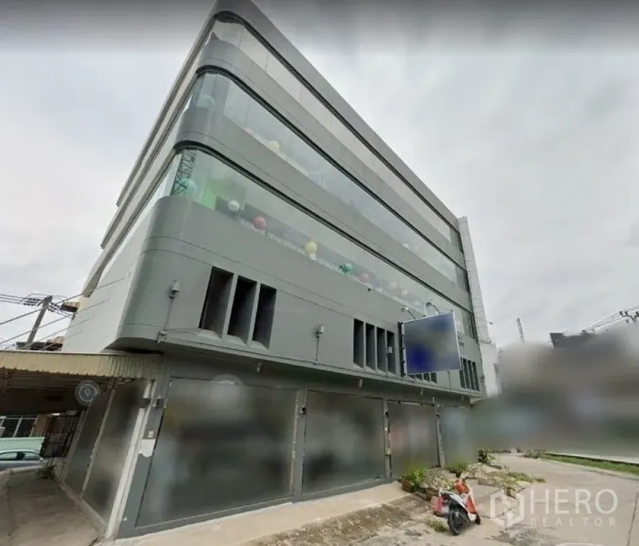 Shophouse for rent in Suan Luang, Bangkok - Contemporary multi-storey shophouse with curved glass façade, grey cladding, ground-floor shutters and a blank signboard in Suan Luang, Bangkok.