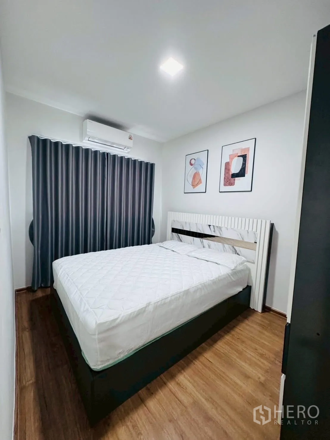 Townhouse for rent in Bang Phli, Samut Prakan - Compact bedroom with double bed, wood floors, blackout curtains and wall-mounted air conditioner.