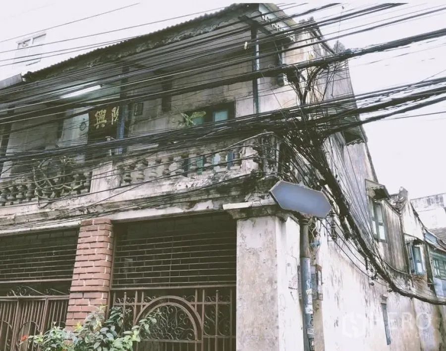 Shophouse for rent in Bang Rak, Bangkok - Street-facing shophouse façade with aging balcony and dense overhead power lines.