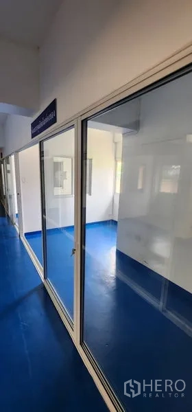 Warehouse for rent in Bueng Kum, Bangkok - Row of sliding glass doors leading to partitioned workspaces with blue flooring.