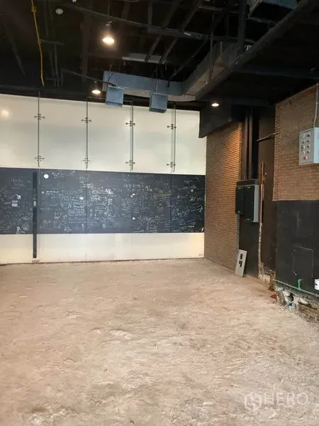 Retail Space for rent in Watthana, Bangkok - Corner of raw unit with brick walls, chalkboard panel and spotlights ready for fit-out.
