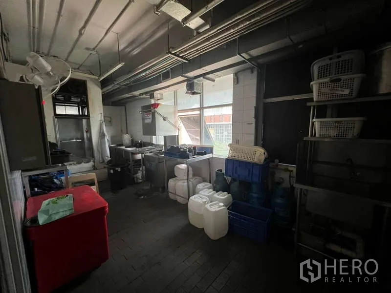 Shophouse for rent or sale in Khlong Toei, Bangkok - Back-of-house prep area with equipment, containers and natural light from the window.