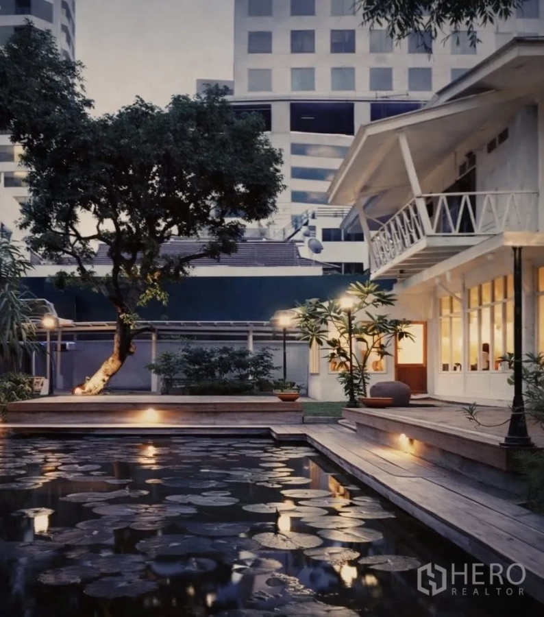 Retail Space for rent in Watthana, Bangkok - Twilight view of landscaped garden with lily pond, wooden deck, and a white two‑storey retail building in Sukhumvit, Bangkok.