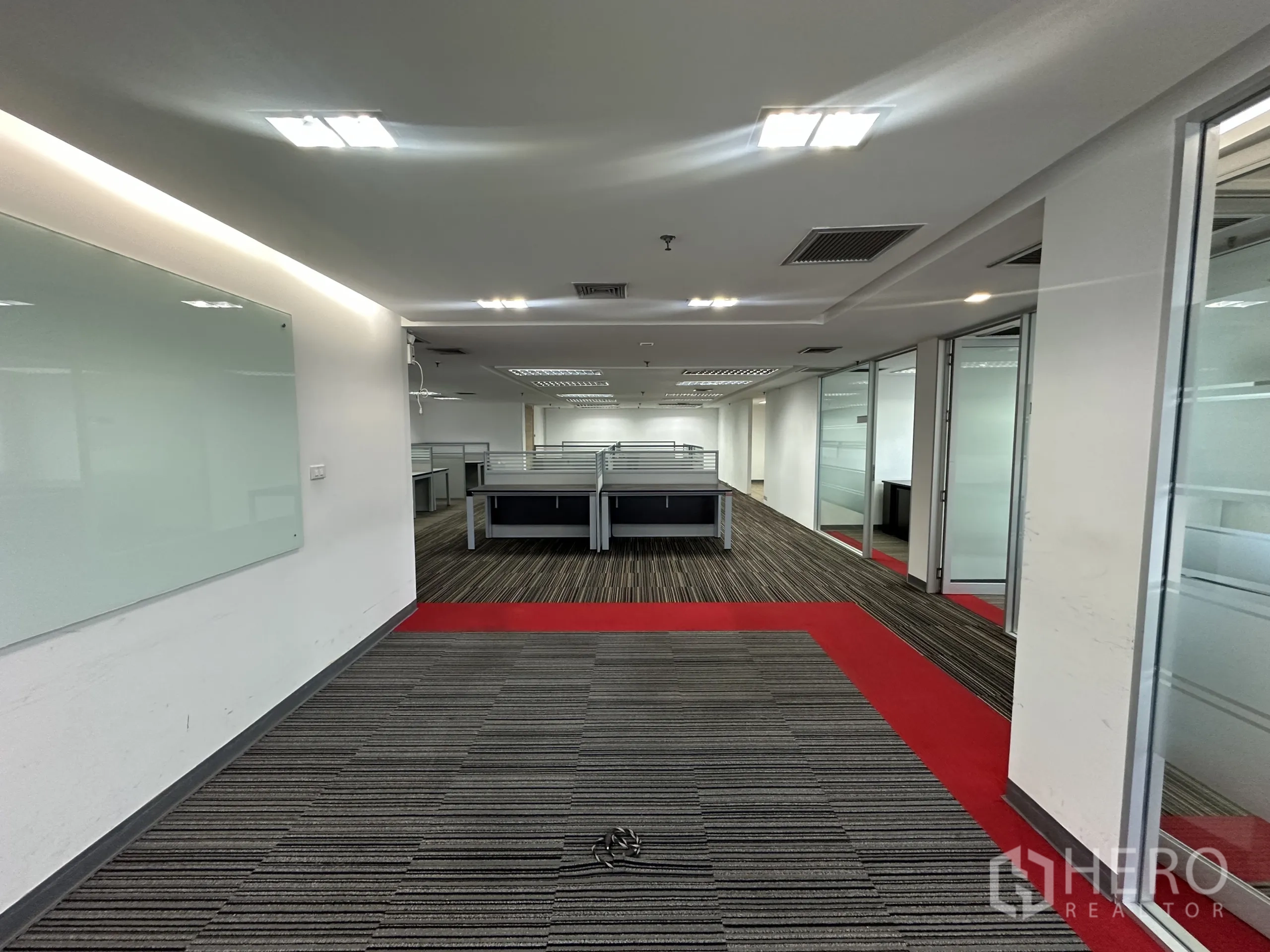 Office Space for rent in Watthana, Bangkok - Hallway leading to workstations with glass meeting rooms and red carpet accents.