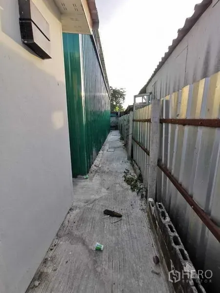 Warehouse for rent in Bang Na, Bangkok - Narrow service alley beside the green warehouse wall and metal fence