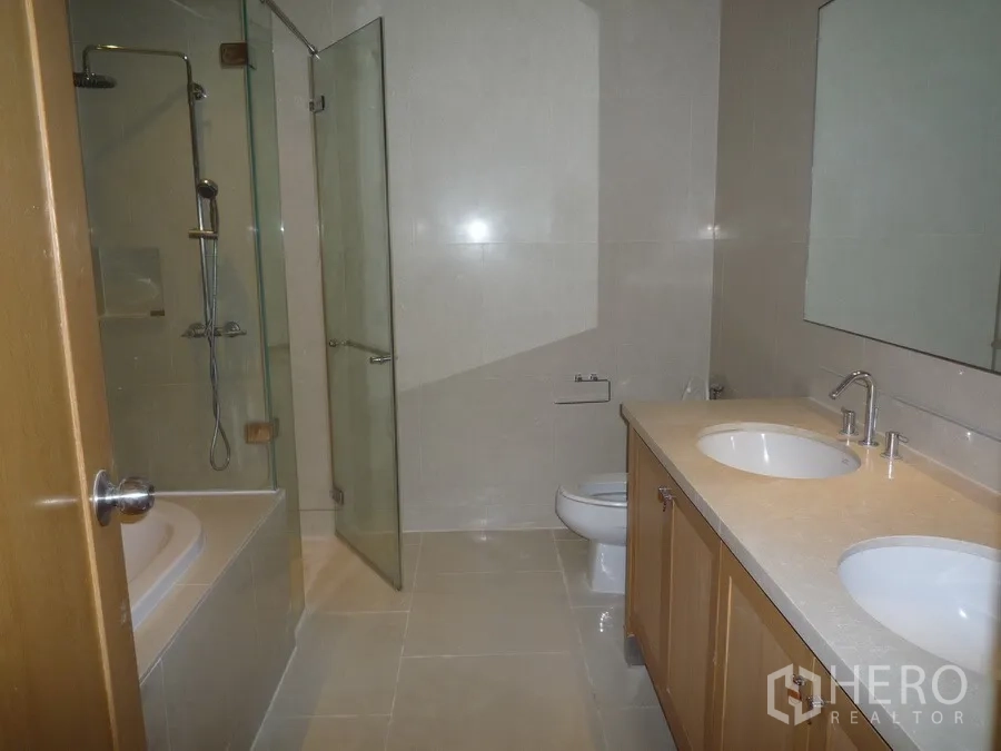 Condominium for rent in Khlong Toei, Bangkok - Modern bathroom with double vanity, glass shower and bathtub.