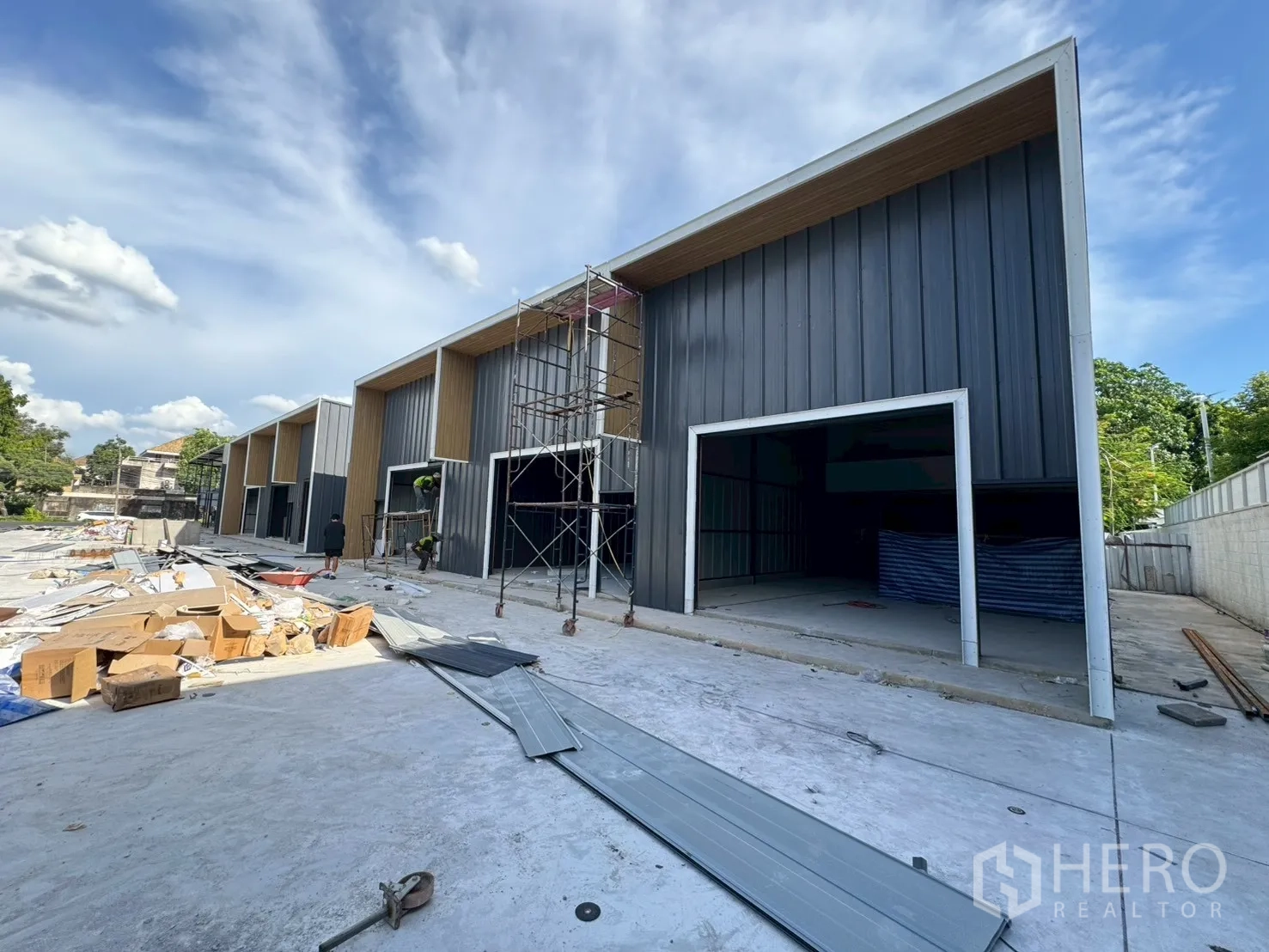 Warehouse for rent in Wang Thonglang, Bangkok - New warehouse units under construction with open roller door frames and scaffolding on the forecourt.
