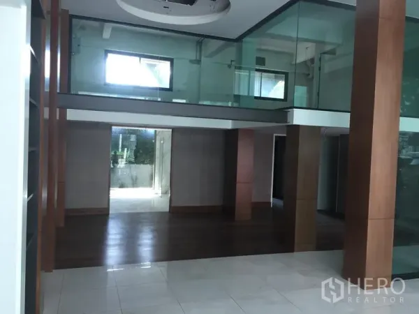 Retail Space for rent in Khlong Toei, Bangkok - Spacious retail interior with double-height ceiling, glass mezzanine and wood columns.