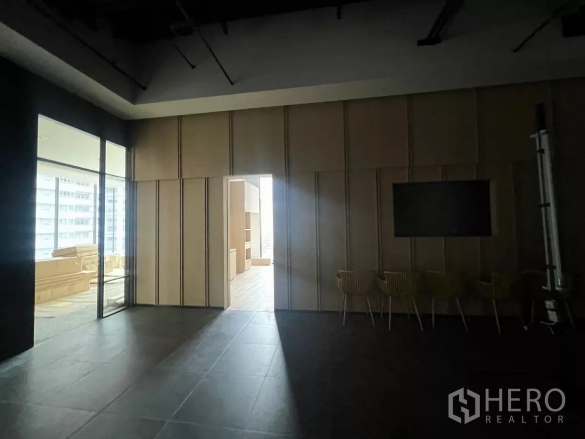 Retail Space for rent - Multipurpose lounge with wood wall panels, glass partitions and seating leading to a brighter showroom.