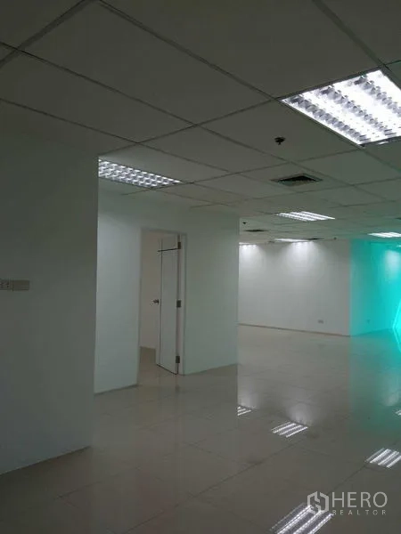 办公空间 出租在Huai Khwang, Bangkok - 办公室一隅，白色墙面、网格吊顶与荧光灯，并设内部门。