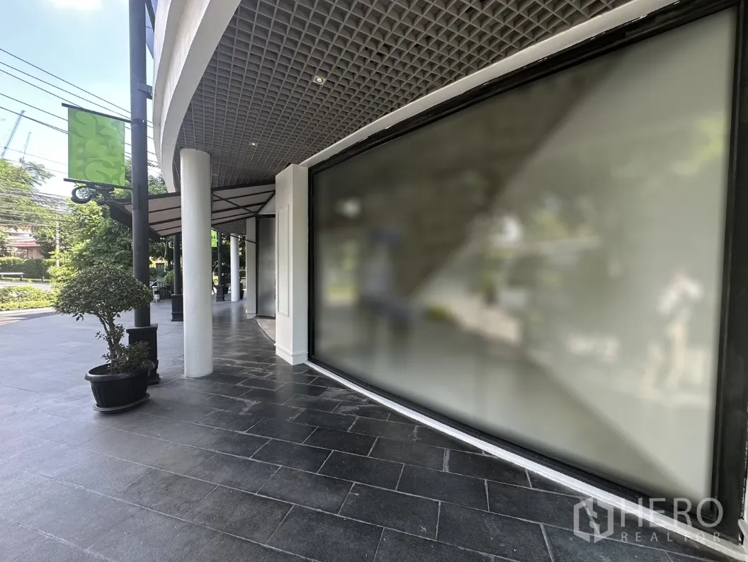 Office Space for rent in Khlong Toei, Bangkok - Street-facing display window and canopy beside a landscaped sidewalk.
