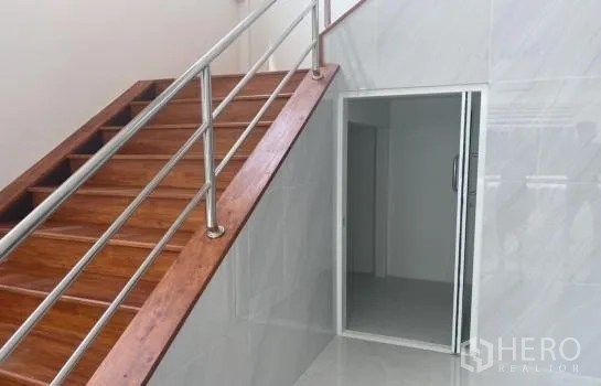 Warehouse for rent in Prawet, Bangkok - Staircase with wooden steps and stainless handrail leading to an upper office room with sliding door.