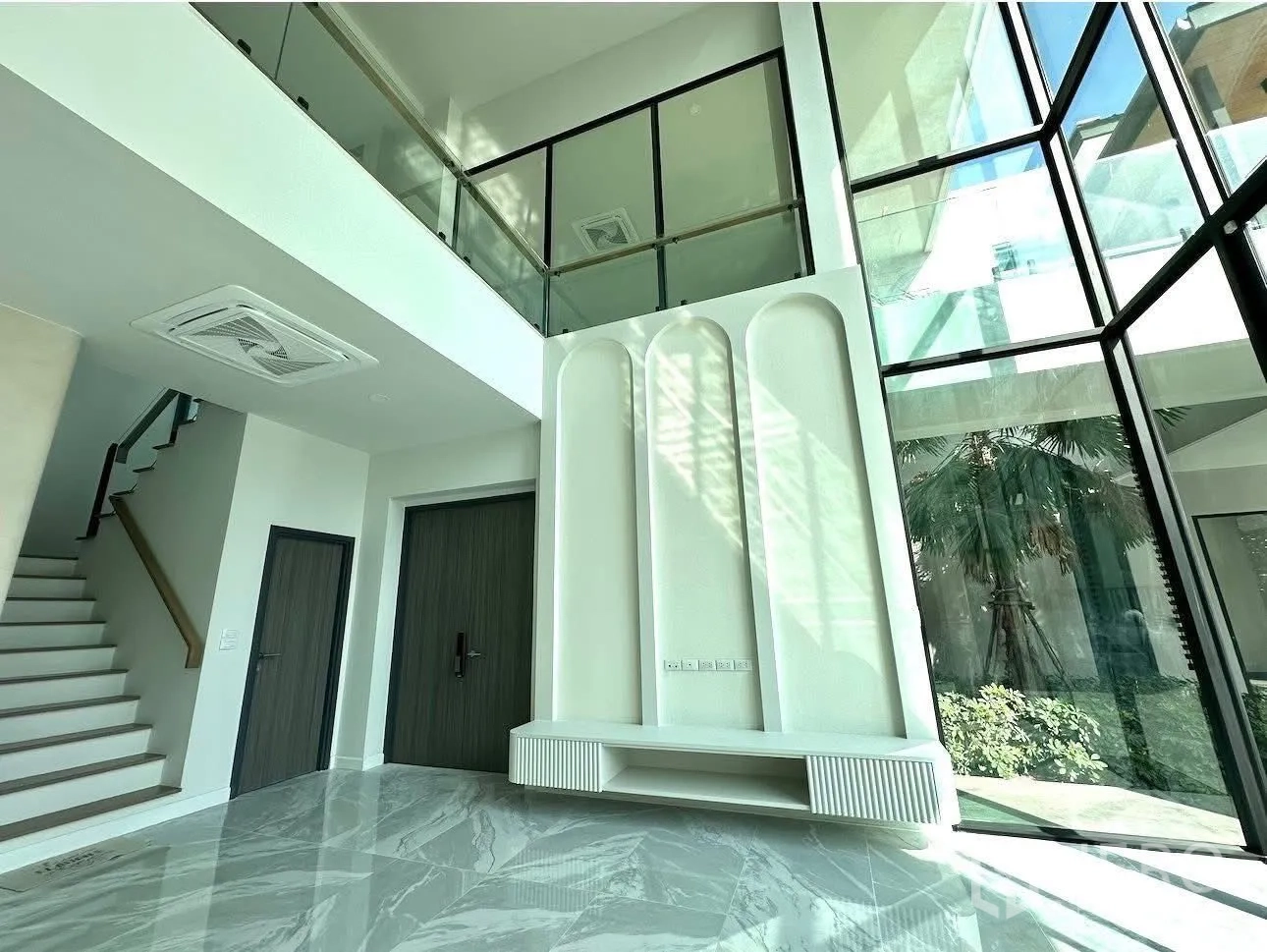 Detached House for sale in Bang Khen, Bangkok - Double-height living area with floor-to-ceiling windows and a mezzanine glass railing.